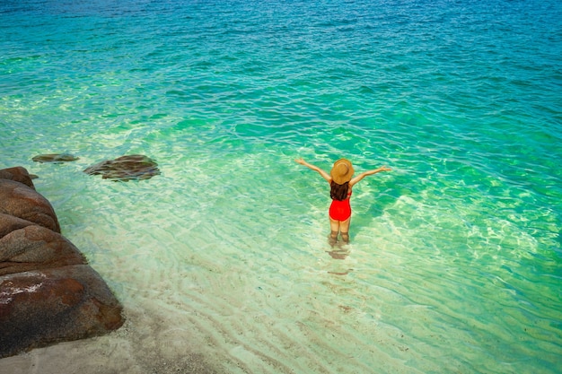 Mujer joven feliz con los brazos levantados en la playa del mar en la isla de Koh MunNork, Rayong, Tailandia