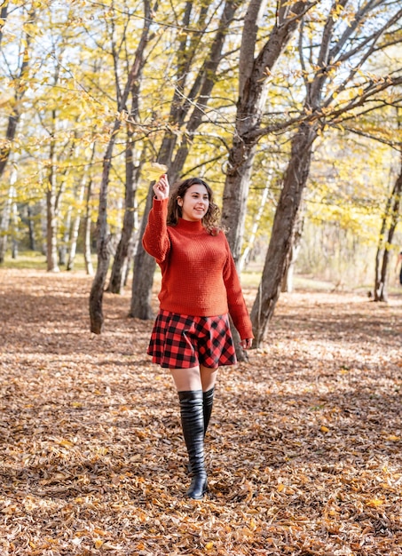 Mujer joven feliz caminando en el bosque de otoño