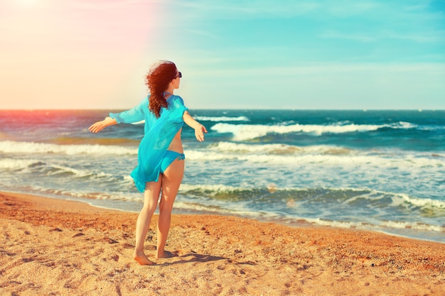 Mujer joven feliz caminando por la playa