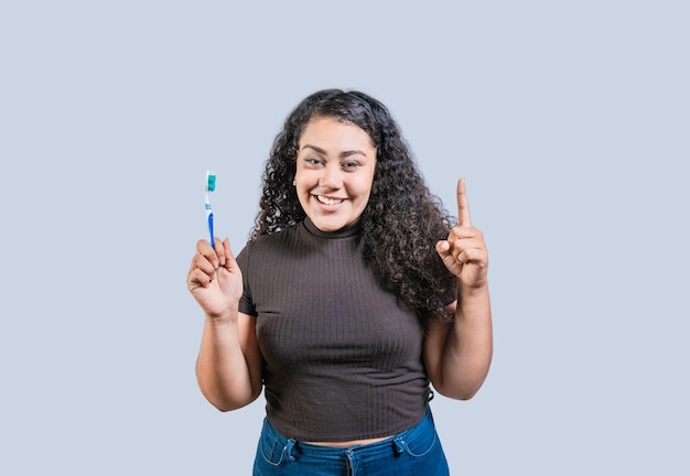Mujer joven feliz con el cepillo de dientes apuntando hacia arriba chica sonriente con el cepillos de dientes y señalando hacia arriba