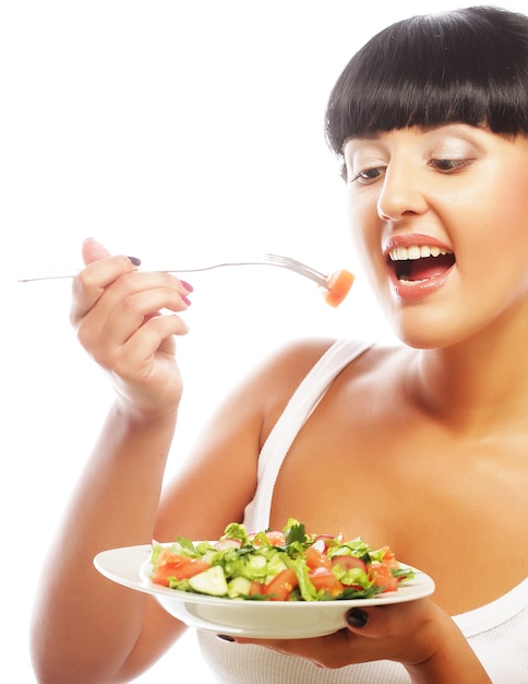 Mujer joven feliz comiendo ensalada