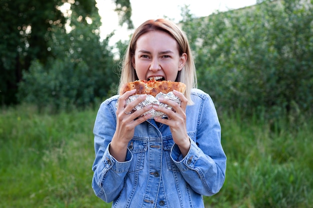 Mujer joven feliz comiendo una hamburguesa