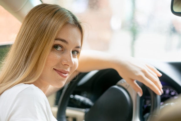 Mujer joven feliz conduciendo un coche caro sonriendo