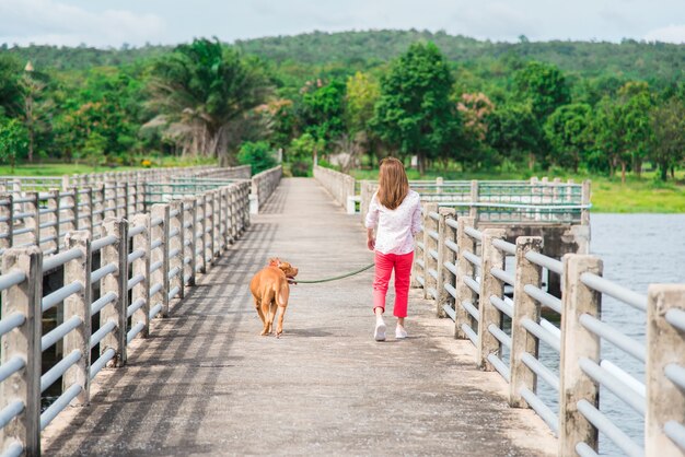 Mujer joven feliz para correr con perro en el parque