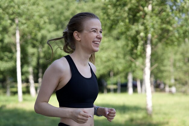 Foto mujer joven feliz corriendo corriendo al aire libre en el parque en el día soleado de verano en la parte superior