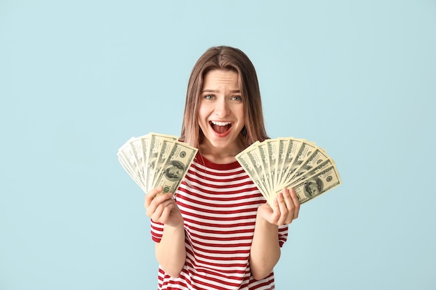 Mujer joven feliz con dinero en azul