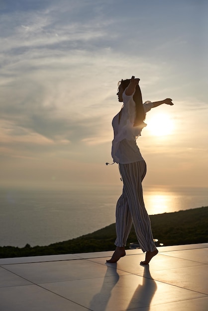 mujer joven feliz disfruta de la puesta de sol mientras baila y disfruta de la música en los auriculares