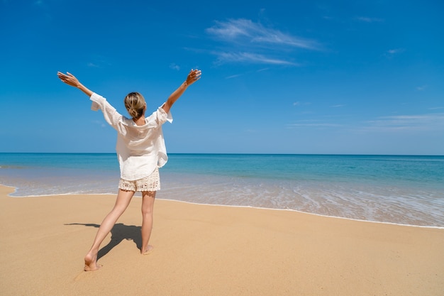 Mujer joven feliz disfrutando de la libertad con las manos abiertas en el mar.