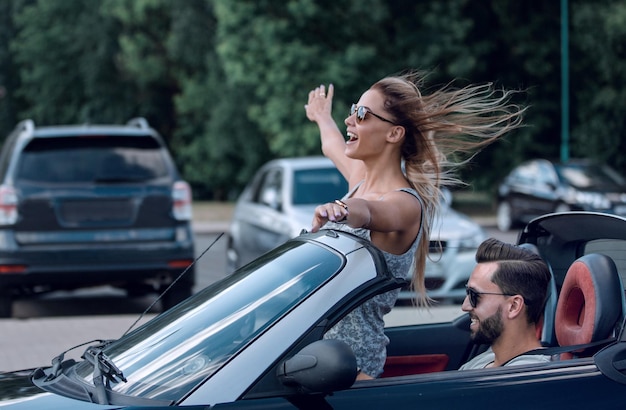 Mujer joven feliz disfrutando de un paseo en un coche descapotable