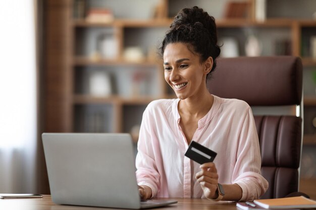 Mujer joven feliz disfrutando de sus compras ilimitadas con tarjeta de crédito en línea