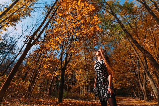 Mujer joven feliz divirtiéndose con hojas en el parque otoño. Espacio para copia.