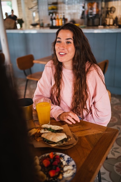 Mujer joven feliz divirtiéndose con sus amigos sentados en un restaurante cafetería brunch