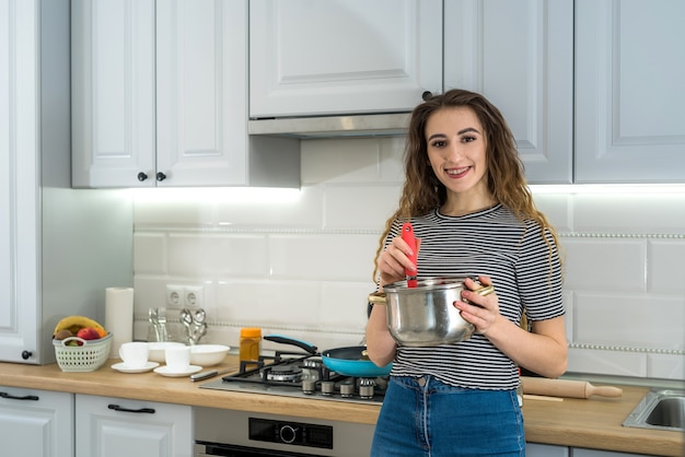 Mujer joven feliz está preparando la cena en la cocina. Estilo de vida femenino saludable. Dieta