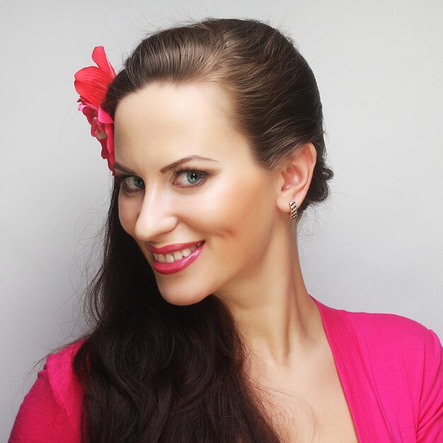 Mujer joven feliz con flor rosa en el pelo