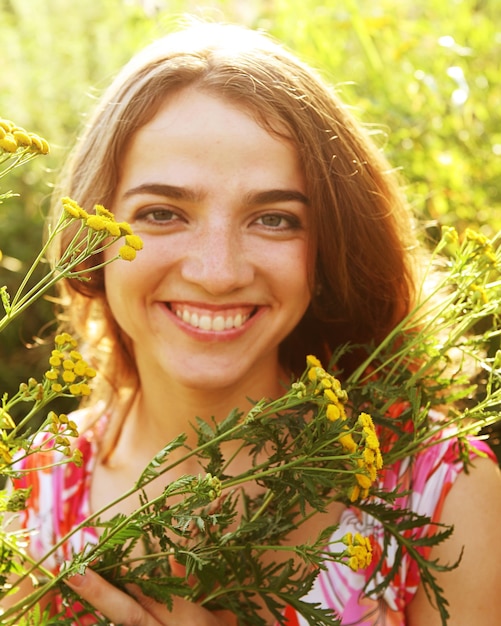 Mujer joven feliz y flores silvestres.