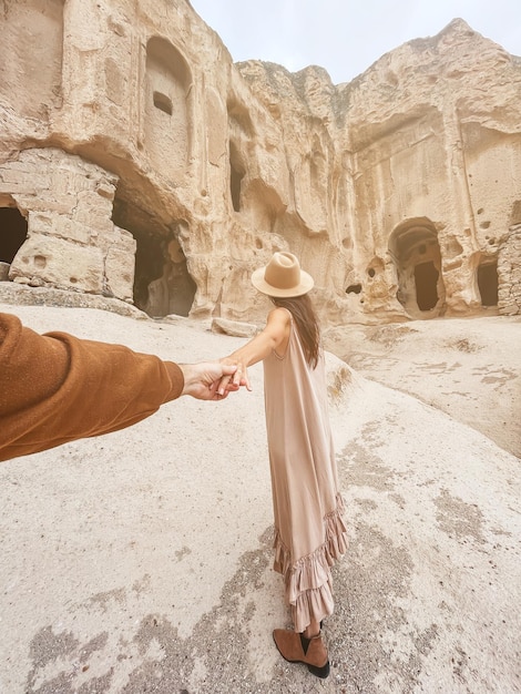 Mujer joven feliz en el fondo de antiguas formaciones de cuevas en capadocia, turquía, el monasterio es uno