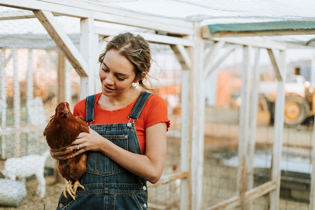 Mujer joven feliz con una gallina marrón