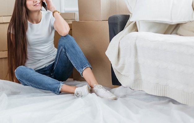 Mujer joven feliz hablando por su teléfono inteligente en su nuevo apartamento. foto con espacio de copia