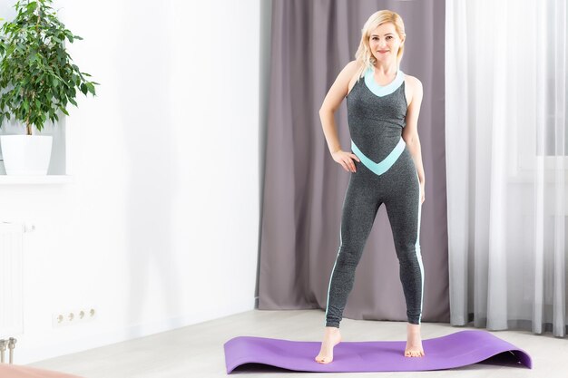 Mujer joven feliz haciendo ejercicios de fitness en casa