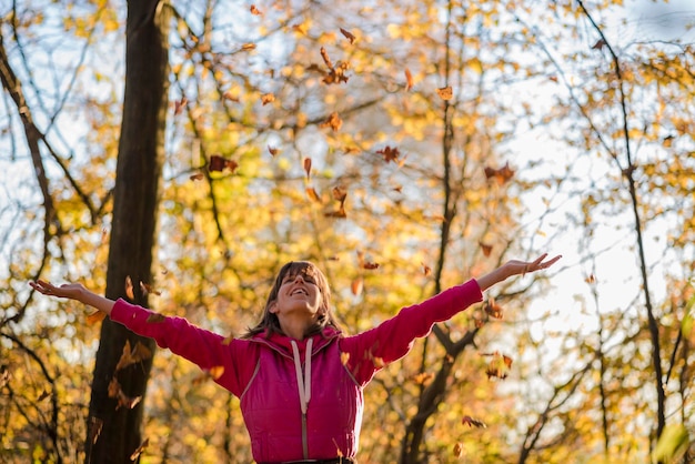 Mujer joven feliz lanzando hojas al aire