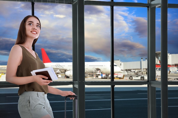 Mujer joven feliz con maleta en el aeropuerto