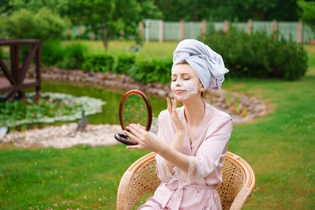 Mujer joven feliz en masaje facial con exfoliante facial orgánico y mirando