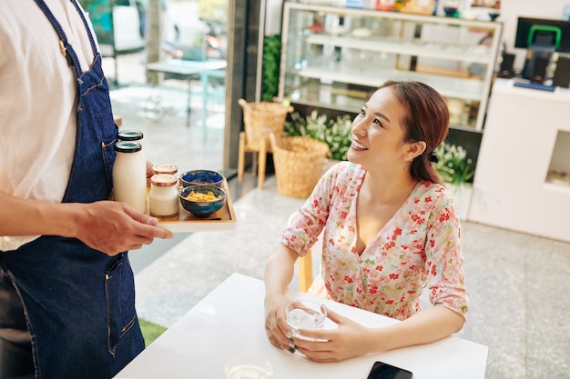 Mujer joven feliz en la mesa de café