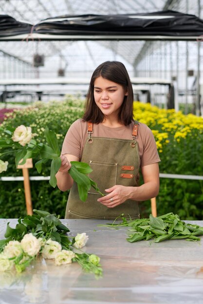 Mujer joven feliz mirando fresca y hermosa flor de eustoma en sus manos