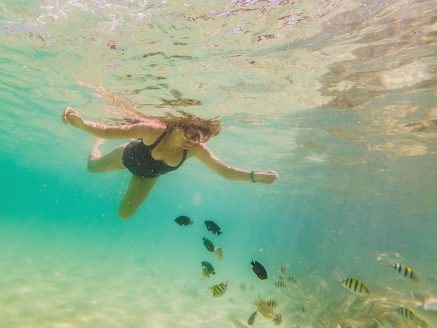 Mujer joven feliz nadando bajo el agua en el océano tropical