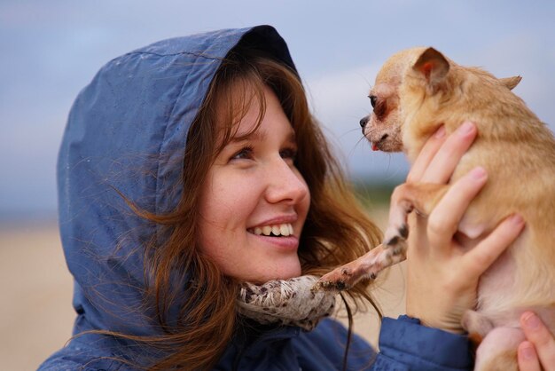 Mujer joven feliz o adolescente caminando con su pequeña mascota chihuahua o juguete perro terrier en el