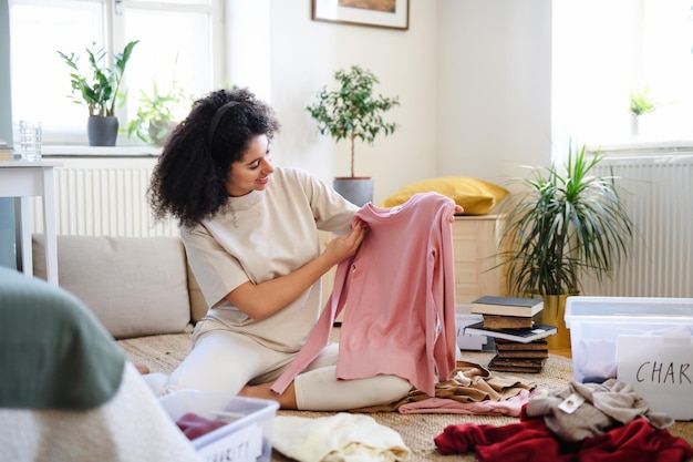 Mujer joven feliz ordenando el armario en el interior de su casa, concepto de donación de caridad.