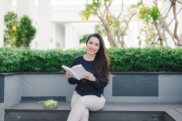 Mujer joven feliz en el parque en el libro de lectura del día soleado de verano. Hermosa chica alegre en un hermoso día.