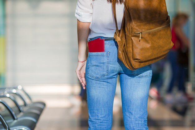 Mujer joven feliz con pasaje aéreo y pasaportes en el aeropuerto esperando el embarque