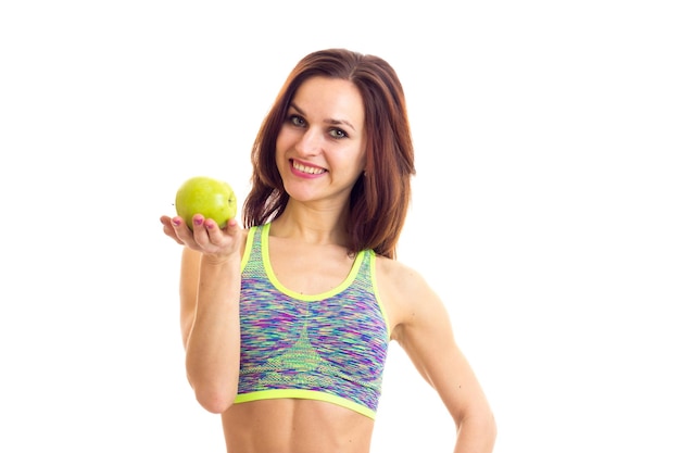 Mujer joven feliz con el pelo largo y castaño en top deportivo de colores con manzana verde