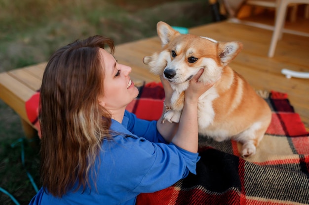 Mujer joven feliz con perro Welsh Corgi Pembroke relajándose en glamping en verano Tienda de campaña de lujo para recreación al aire libre y recreación Concepto de estilo de vida