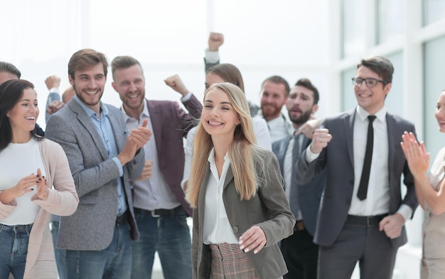 Mujer joven feliz de pie frente a sus colegas jubilosos