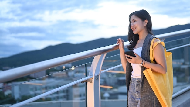 Mujer joven feliz de pie en la terraza de la azotea con un hermoso cielo nocturno en segundo plano.