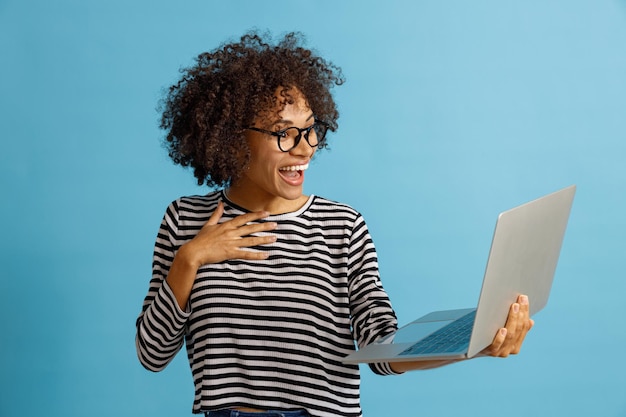 Mujer joven feliz con portátil en estudio