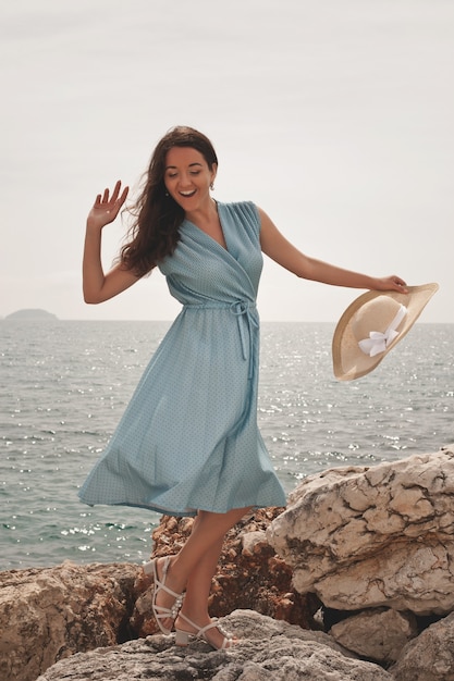 Mujer joven feliz posando cerca del mar, vacaciones de verano