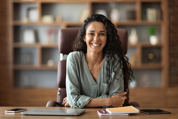 Mujer joven feliz posando en el escritorio en la oficina