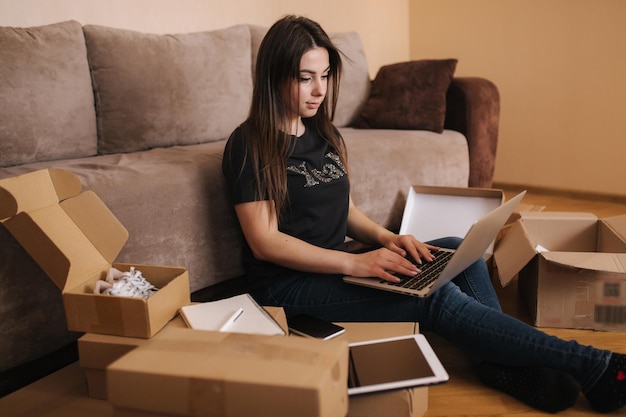 Mujer joven feliz que compra en línea usa una computadora portátil y una tableta para buscar nuevos productos atractivos