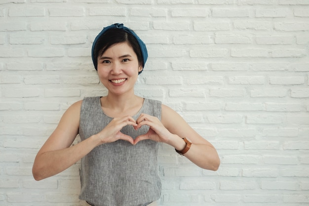 Mujer joven feliz que hace sus manos en él forma