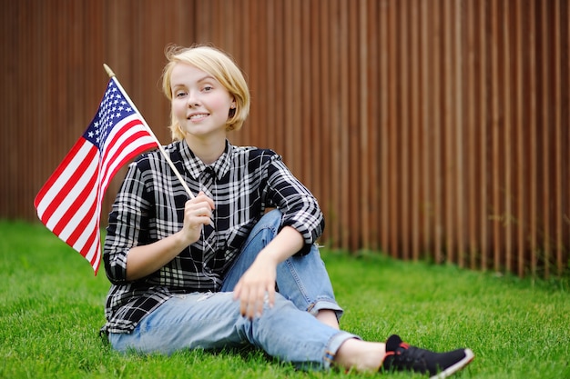 Mujer joven feliz que sostiene la bandera americana. Concepto de día de la independencia.