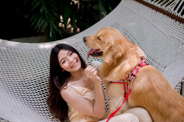 Mujer joven feliz que sostiene el golden retriever del perro.