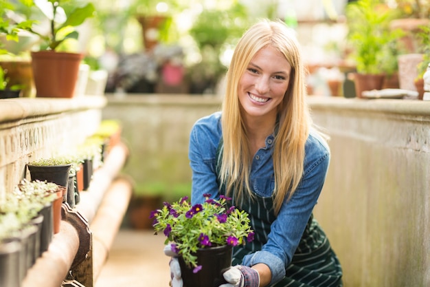 Mujer joven feliz que sostiene la planta floreciente