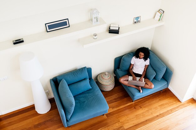 Foto mujer joven feliz que usa la computadora portátil en casa