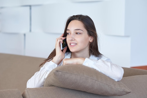 mujer joven feliz que usa el teléfono celular en casa y se relaja