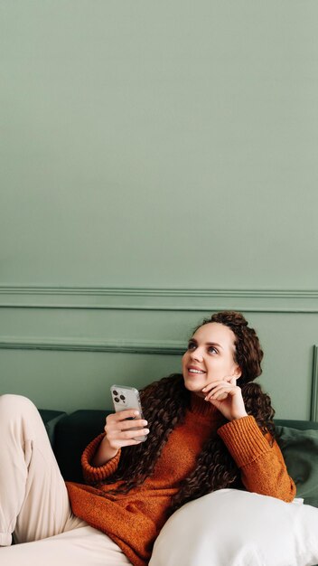 Mujer joven feliz que usa el teléfono celular para compras de comercio electrónico y entretenimiento en casa mujer alegre