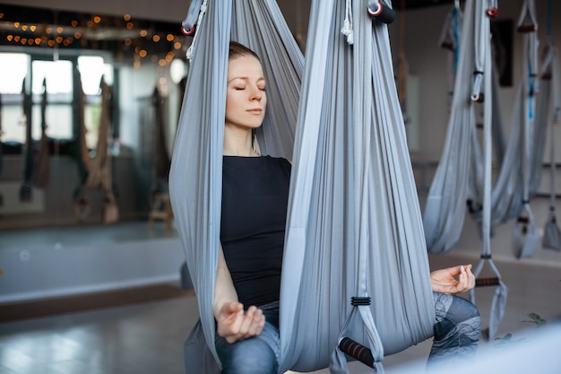 Una mujer joven feliz realiza ejercicios de yoga con una hamaca