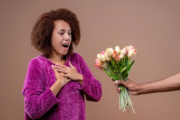 Mujer joven feliz recibiendo flores y luciendo complacida